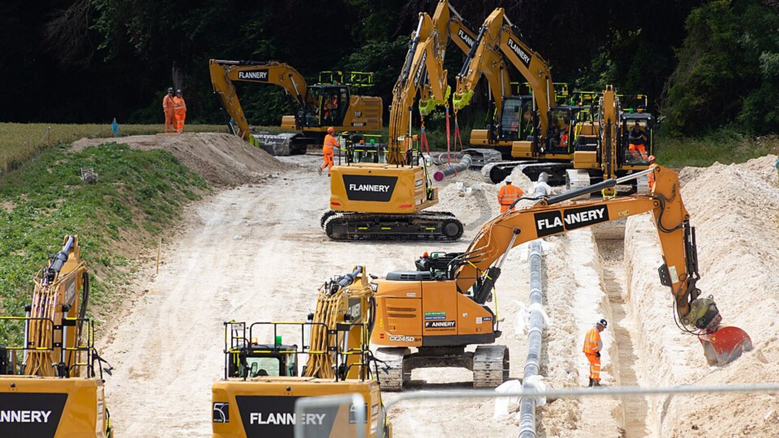 Multiple excavators and crew installing utility pipe on a large worksite